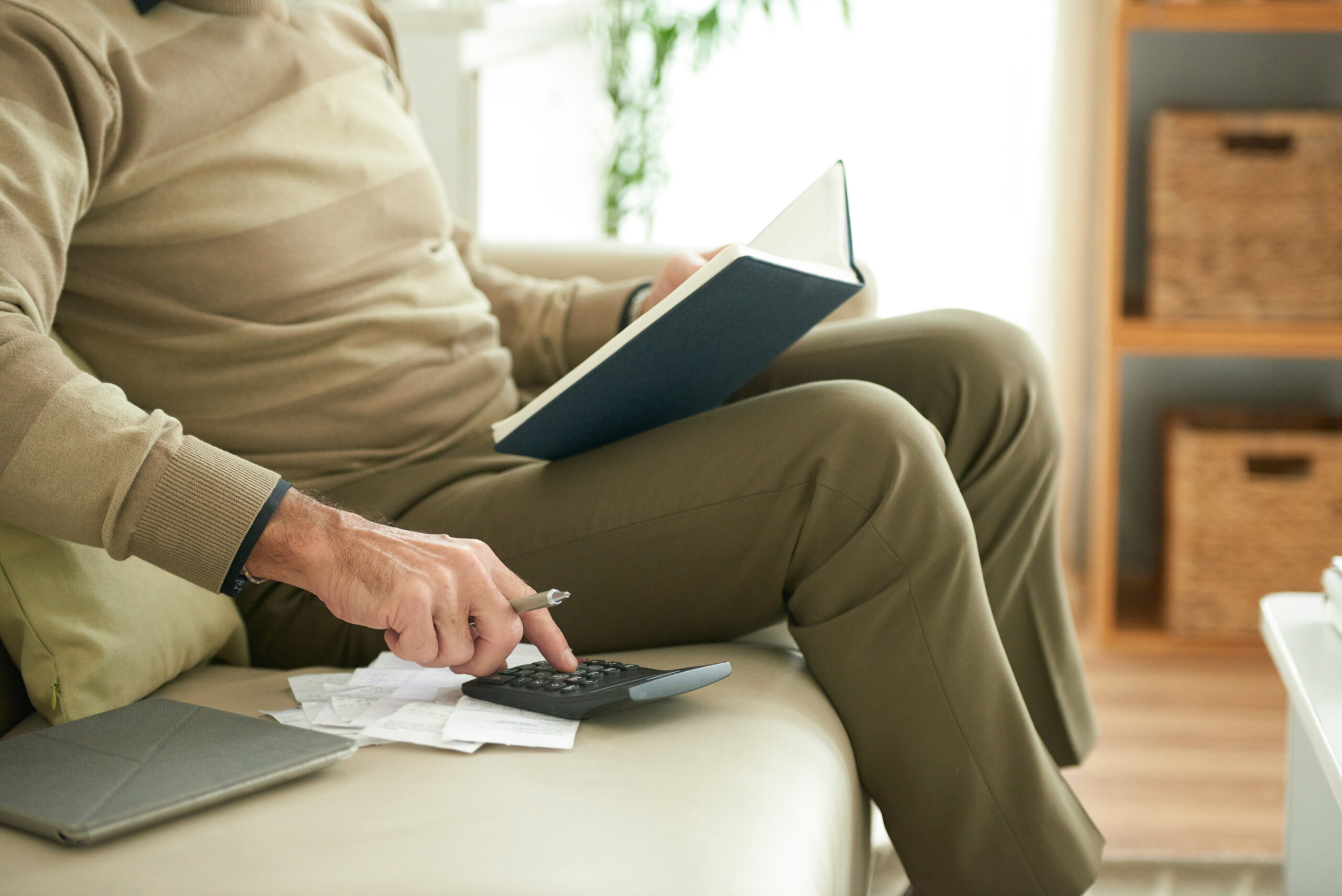 Cropped image of aged man checking his bills and credit payments